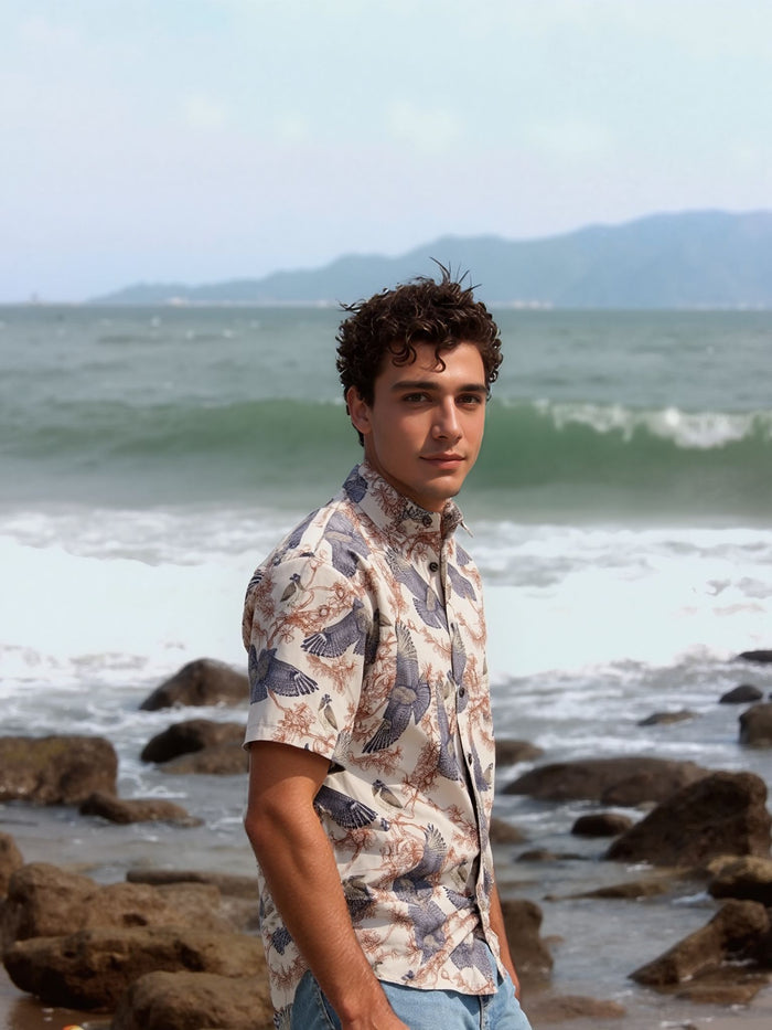 Person standing on a rocky beach with ocean and mountains in the background