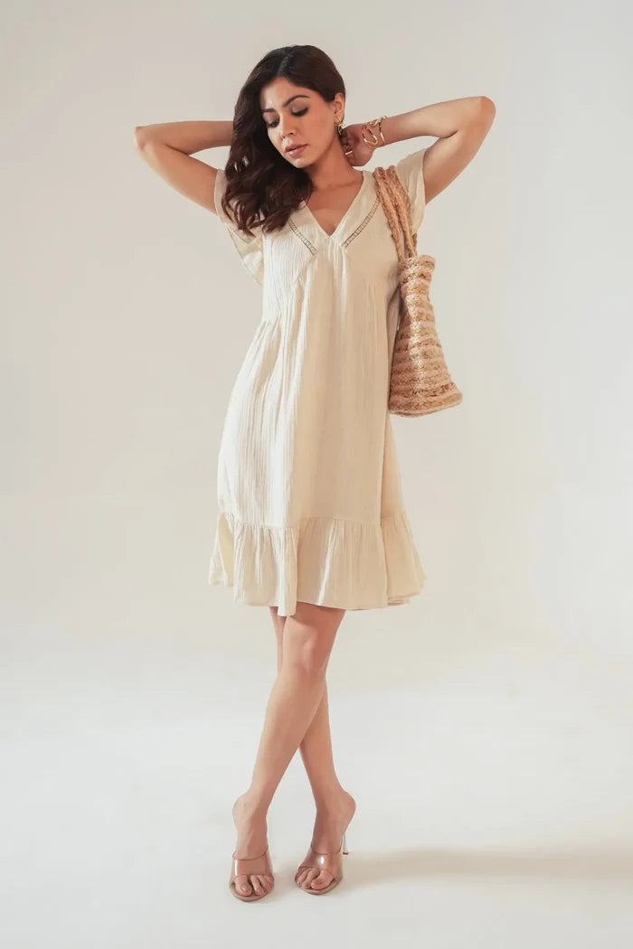 Model posing with bag in beige cotton cottagecore women’s dress with lace insert and ruffle hem – feminine summer outfit