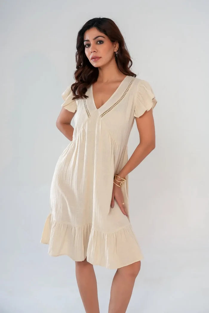 Side angle of women’s beige cotton cottagecore dress featuring lace insert neckline, ruffle sleeves and relaxed fit