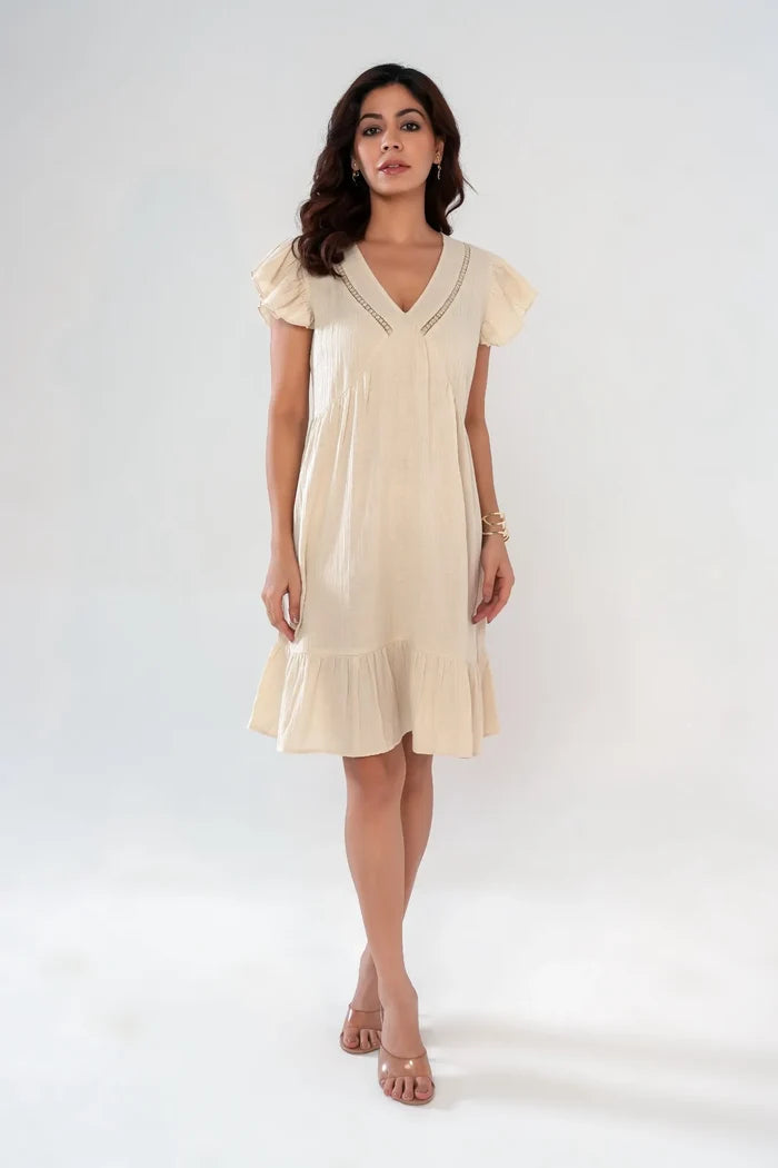Woman wearing beige cotton cottagecore women’s dress with lace insert, ruffle sleeves and flared hem – front view