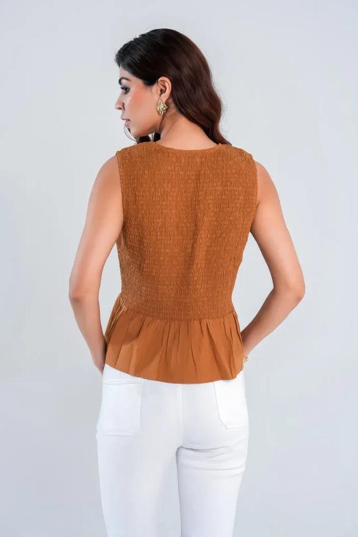 Back view of brown sleeveless top with textured smocked bodice and peplum hem