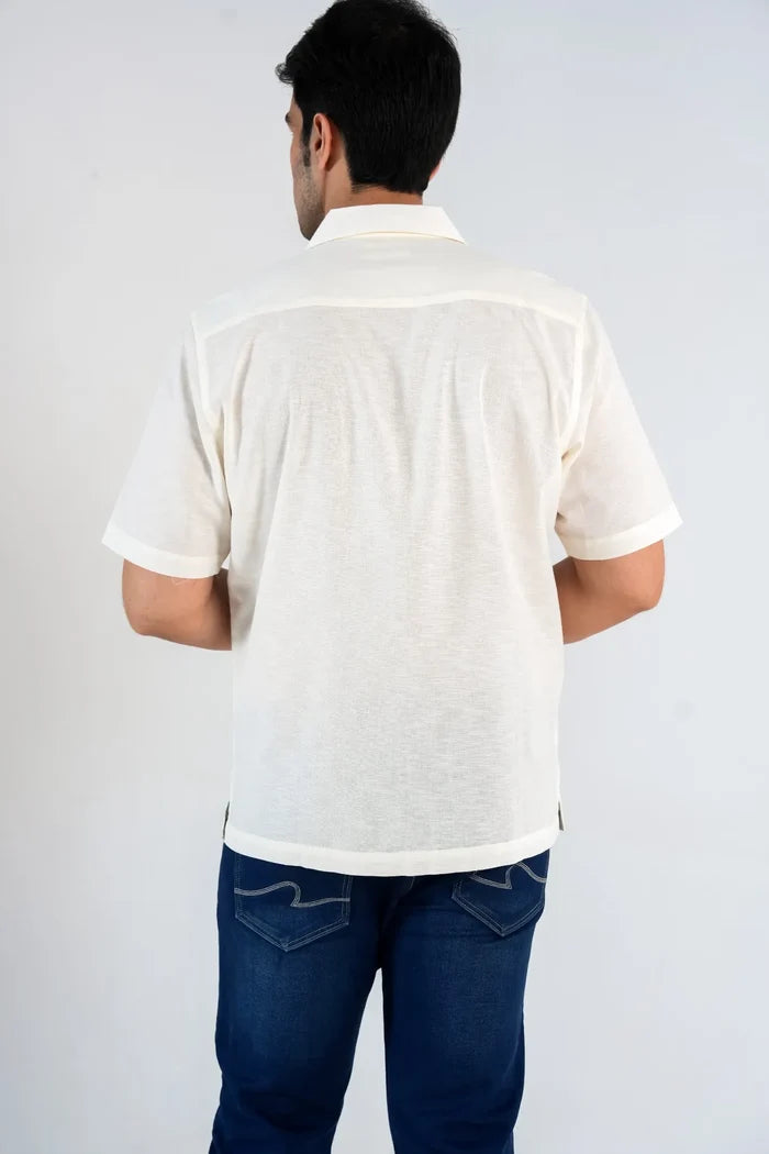Man wearing a white polo shirt and blue jeans on a plain background