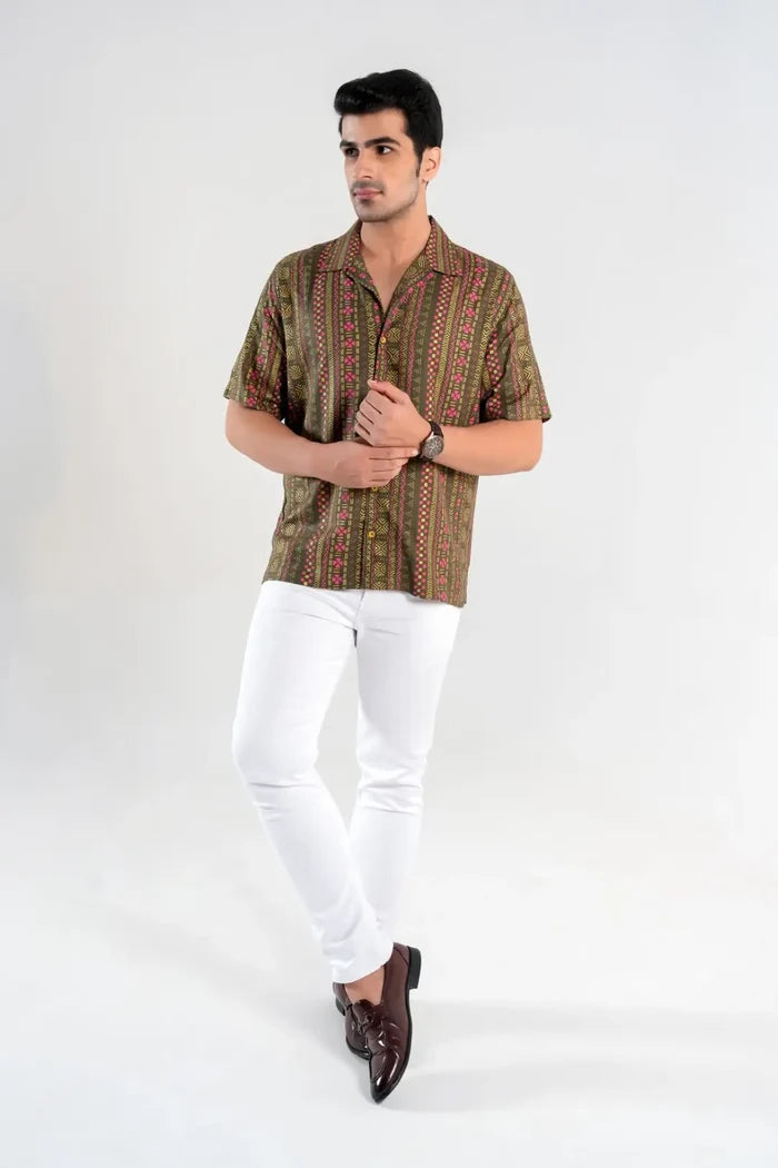 Man wearing olive green oversized geometric print shirt with white pants and brown loafers