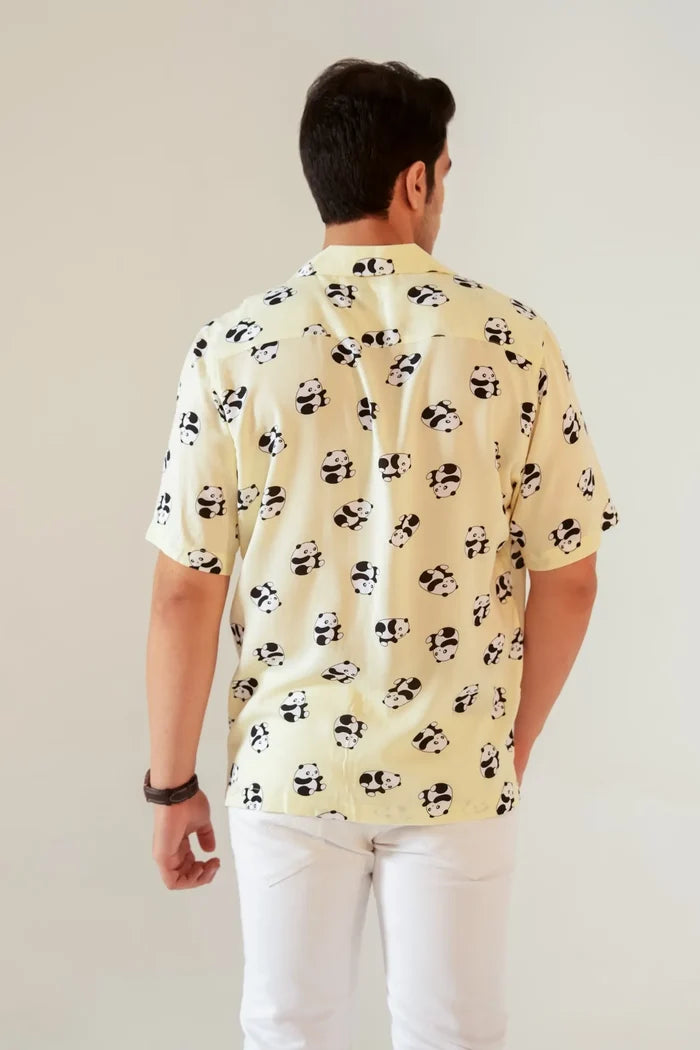 Man wearing a light yellow shirt with black patterns against a plain background