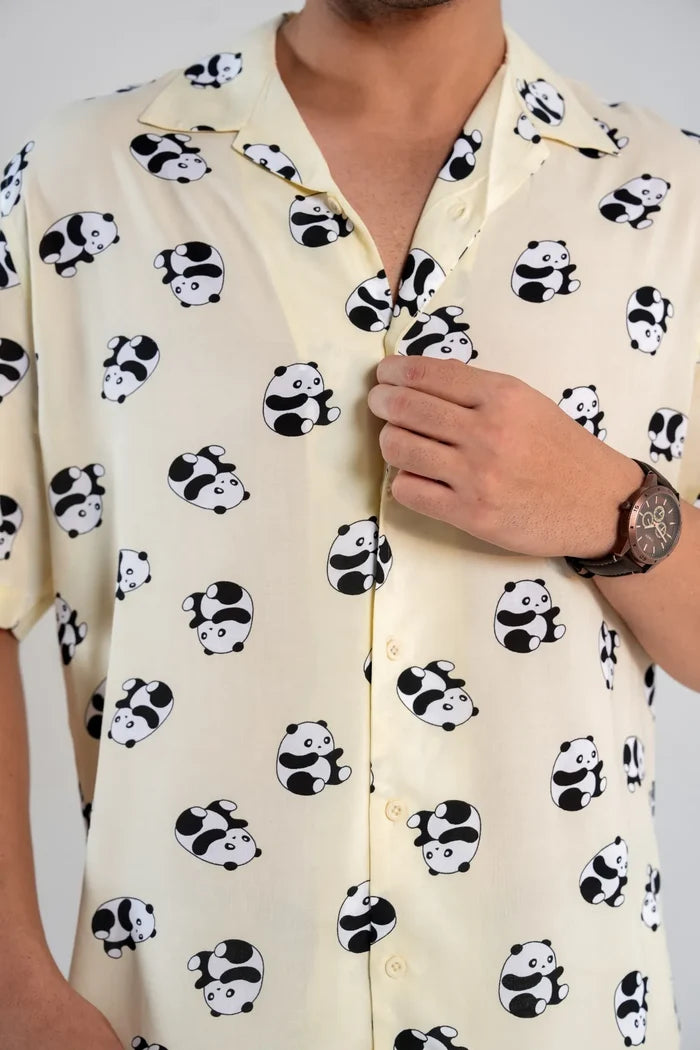 Person wearing a yellow shirt with panda pattern on a plain background