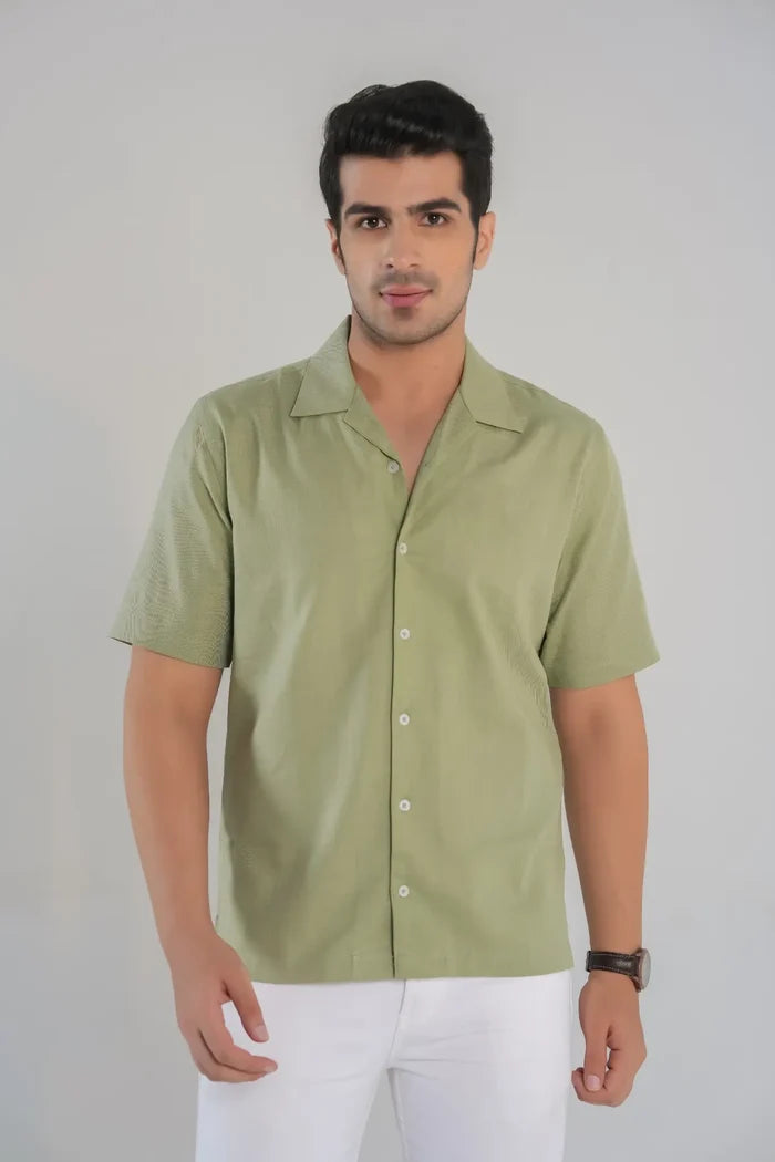 Man wearing a light green shirt and white pants against a plain background