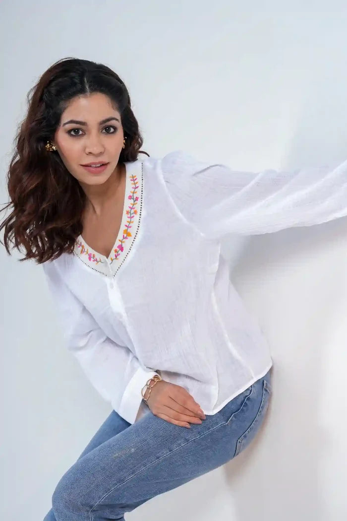 Casual pose in white textured cotton shirt with multicoloured embroidered neckline
