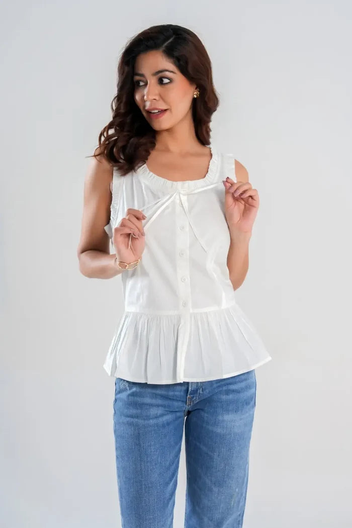 Model holding tie-front accent with hand on white sleeveless cotton cottagecore peplum, featuring frill neckline – feminine summer outfit