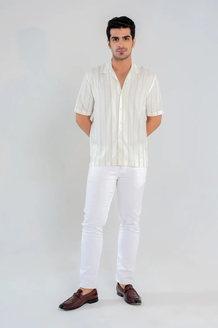 Man wearing white and blue vertical striped Cuban collar shirt with white pants – full front view